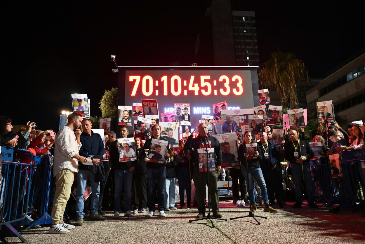 Families of Israeli hostages lift placards depicting their relatives.