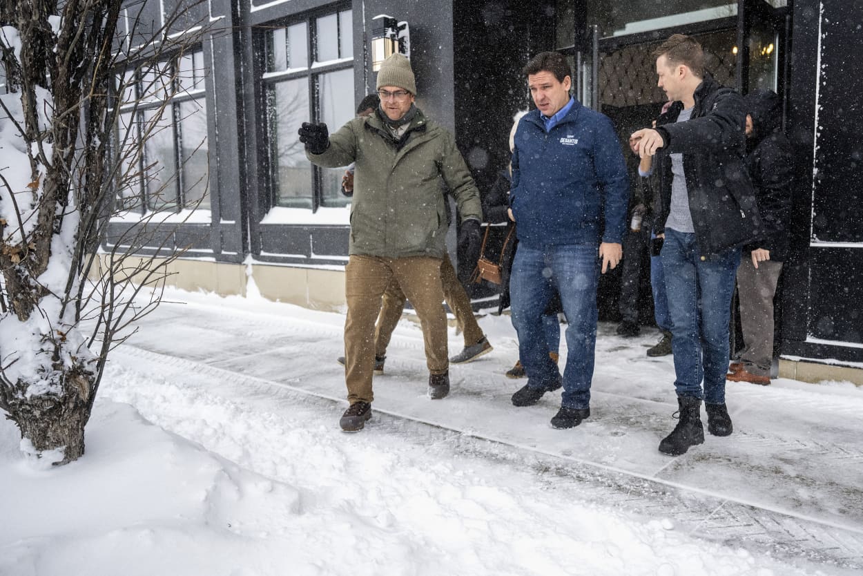 Florida Gov. Ron DeSantis is guided to his vehicle by staff as he departs a campaign stop in Ankeny, Iowa, on Jan. 12, 2024. 