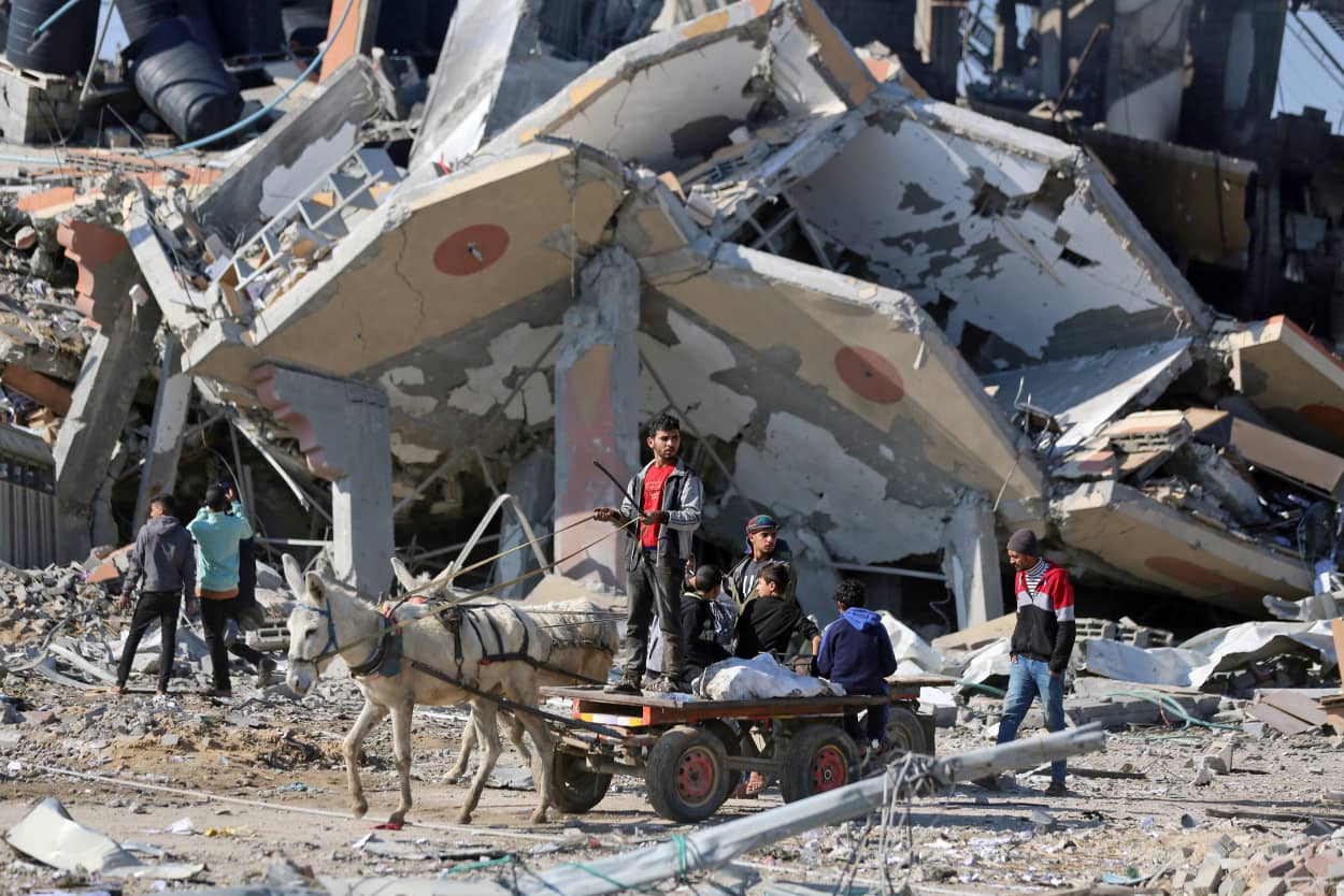 A donkey cart drives past a collapsed building in the Al-Maghazi refugee camp in central Gaza Strip, on Jan. 16, 2024.