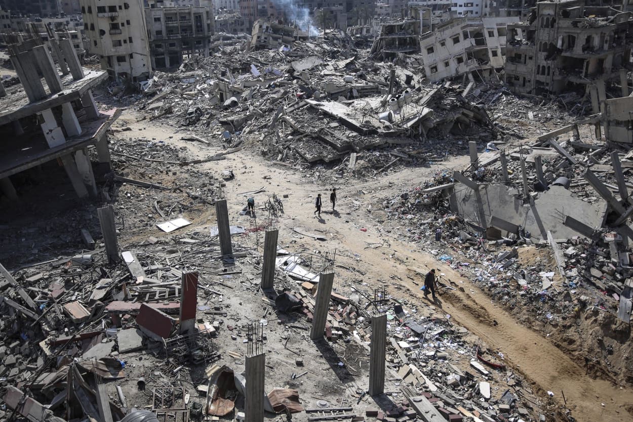 Palestinians walk amid the destruction in the vicinity of al-Shifa Hospital, following a two-week military operation by the Israeli army in Gaza City, on April 2, 2024.