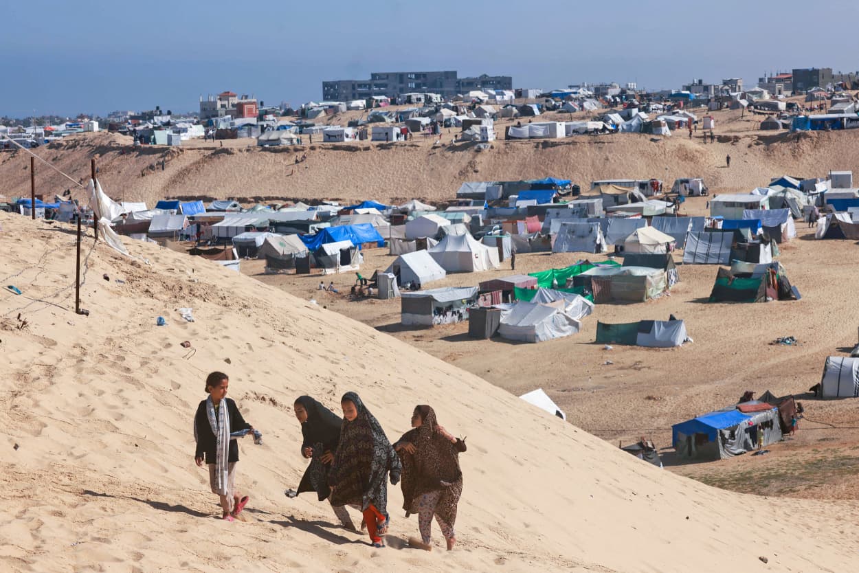 Palestinian girls next to a makeshift tent camp for displaced people in Rafah in the southern Gaza Strip on April 4, 2024.