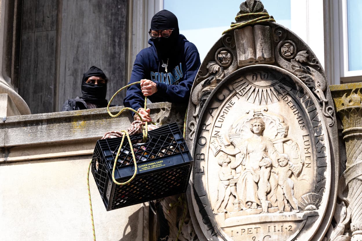 Pro-Palestinian protestors who are occupying Hamilton Hall lift a milk crate with supplies at Columbia University.