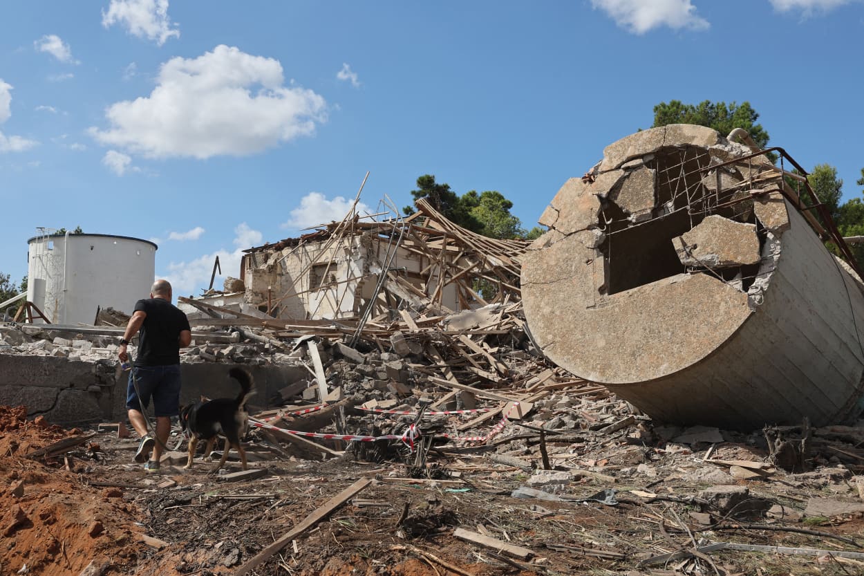 A man walks with a dog past the rubble of a destroyed building in Hod HaSharon, Israel, in the aftermath of an Iranian missile attack.