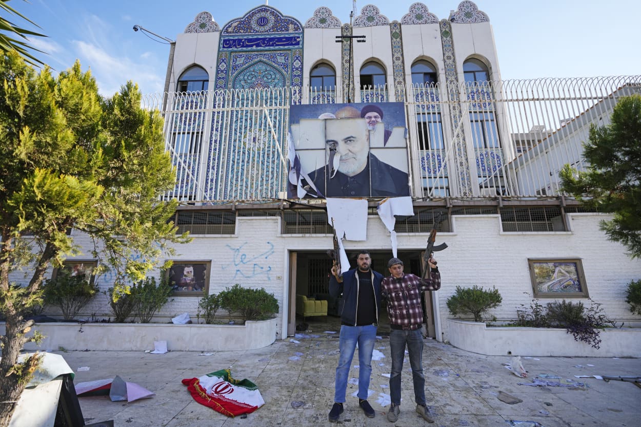 Syrian opposition fighters stand at the entrance to the ransacked Iranian embassy in Damascus on Dec. 8, 2024. 