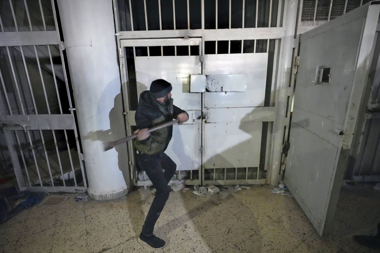 A man breaks the lock of a cell in the infamous Saydnaya military prison, just north of Damascus, Syria, Monday, Dec. 9, 2024. 