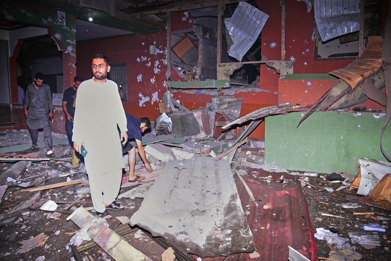 Local residents examine a building damaged from a suspected Indian missile attack near Muzaffarabad