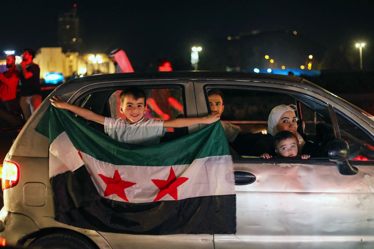 A young boy holds a Syria flag from a car in Damascus' Omeyyad square