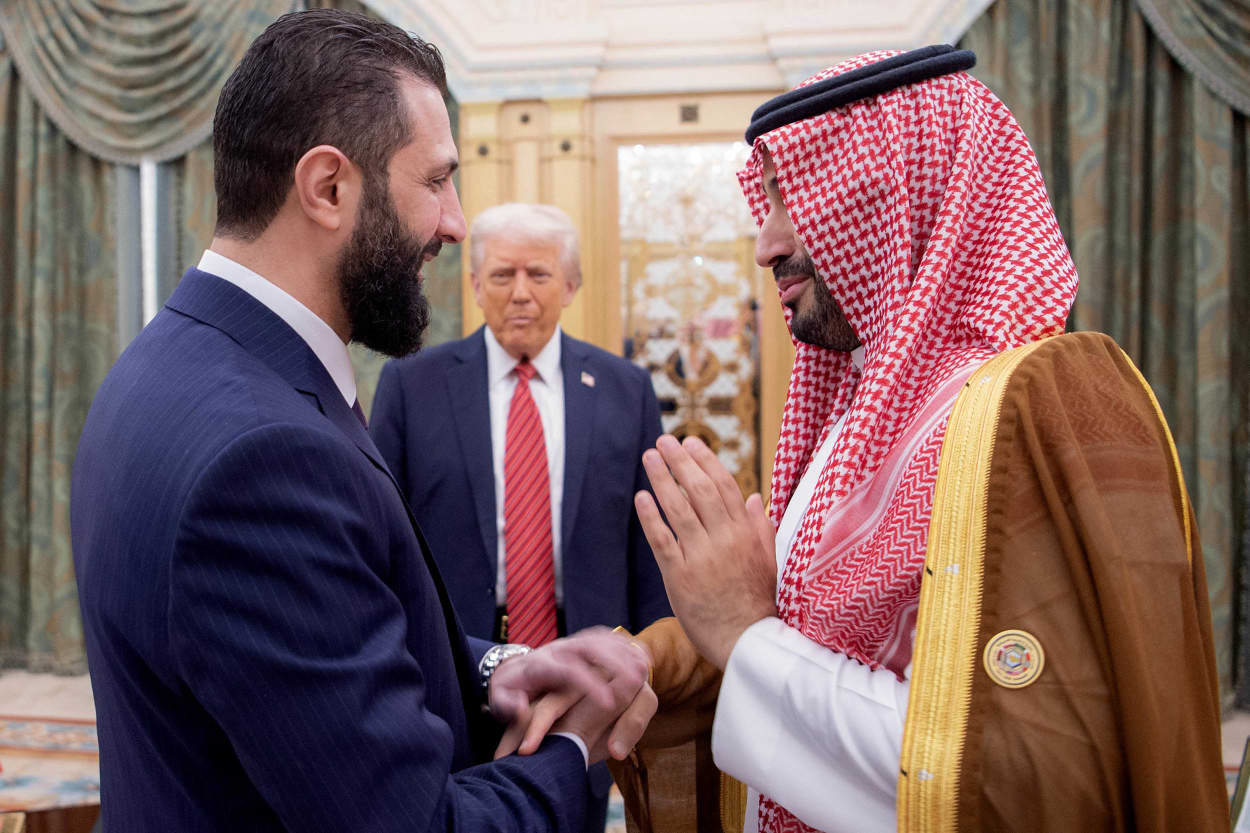 Saudi Crown Prince Mohammed bin Salman shakes hands with Syria's interim president Ahmed al-Sharaa as US President Donald Trump looks on.