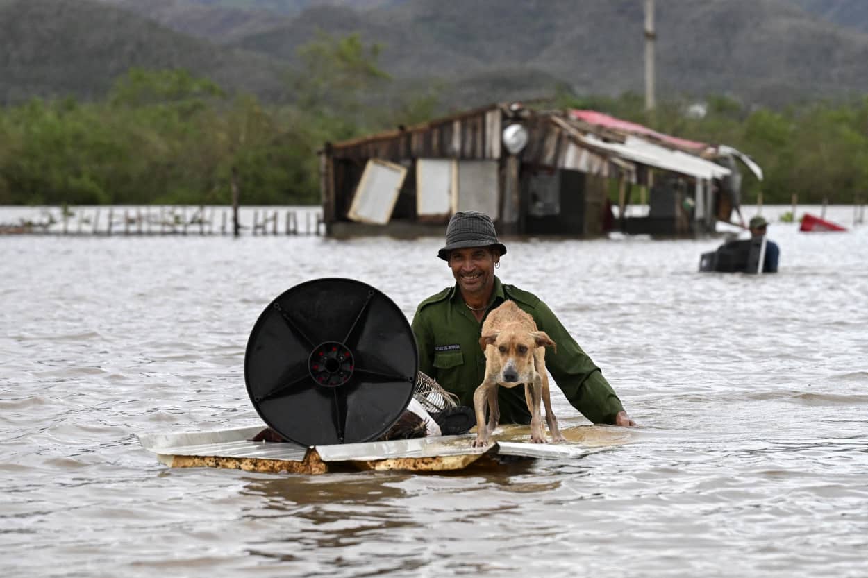 A farmer rescues his dog and some belongings from his flooded house after Hurricane Melissa passed through the town of San Miguel de Parada in Santiago de Cuba province on October 29, 2025.