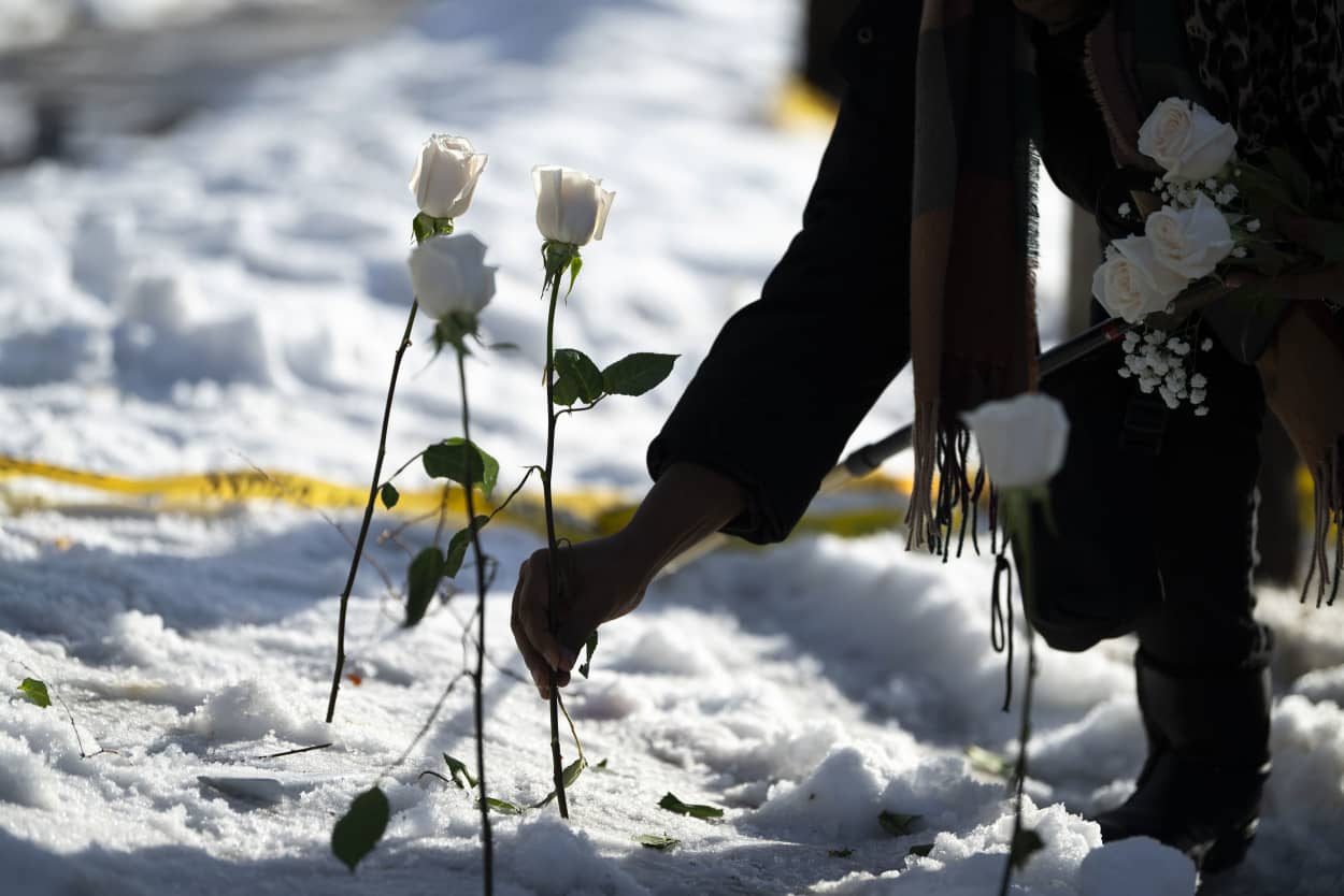A woman places a rose in the snow.