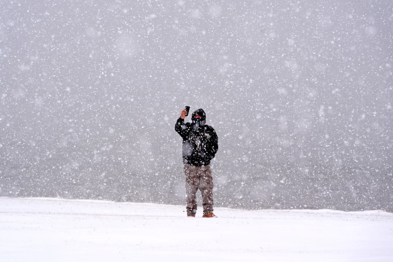 A man taking photos of heavy snow falling.