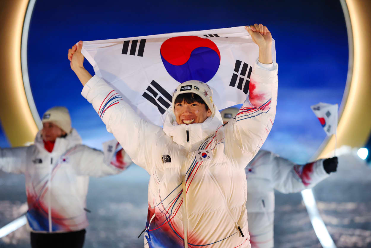 A group of athletes from Republic of Korea walk into the Olympic ceremony while holding their flag up. 