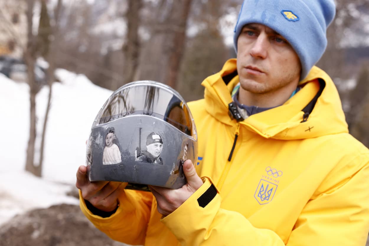 Ukraine's skeleton racer Vladyslav Heraskevych holds his helmet, which depicts victims of his country's war with Russia, in Cortina d'Ampezzo.