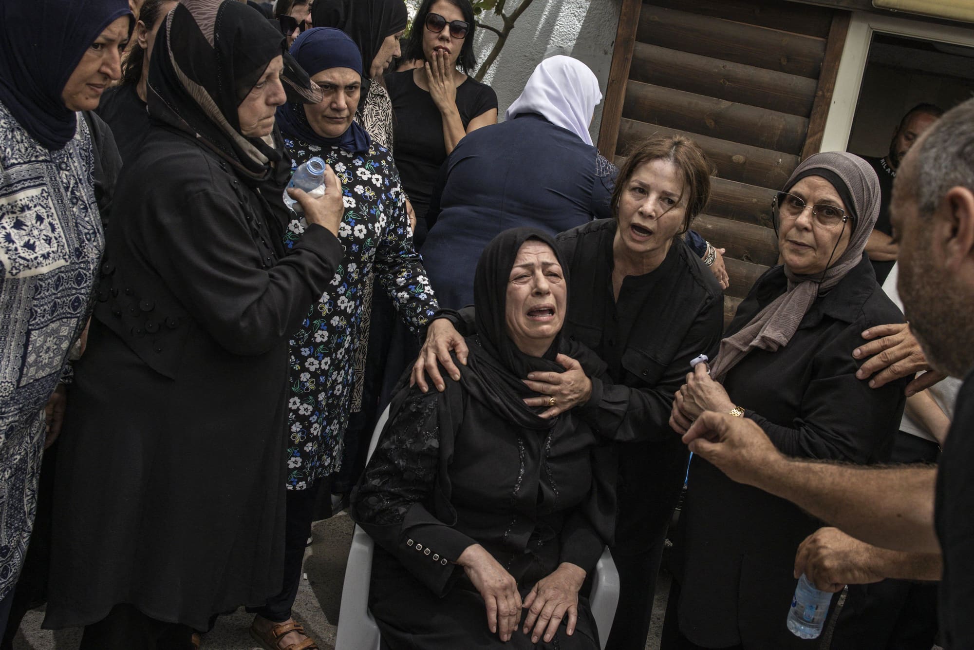 The mother of one of the victims of an Iranian missile attack which destroyed a three-storey building in the northern Arab-Israeli city of Tamra, is comforted during a funeral on June 17, 2025.