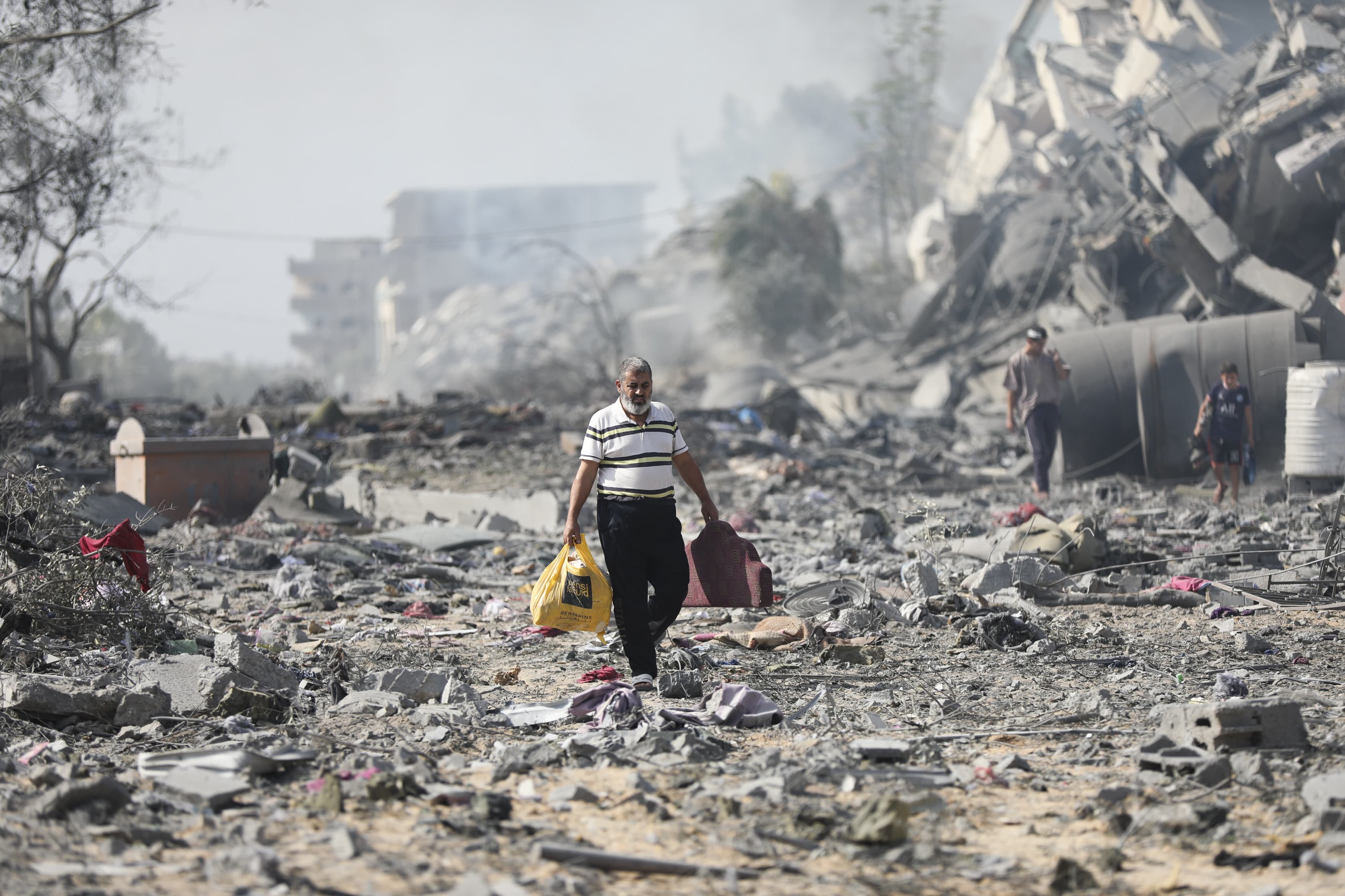 A Palestinian man walks through debris next to buildings destroyed in an Israeli bombardment on al-Zahra, on the outskirts of Gaza City, Friday, Oct. 20, 2023.