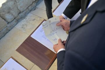 Benjamin Netanyahu holds a note containing a prayer into the Western Wall that says: “The people have risen as a lion. Am Israel Chai!”