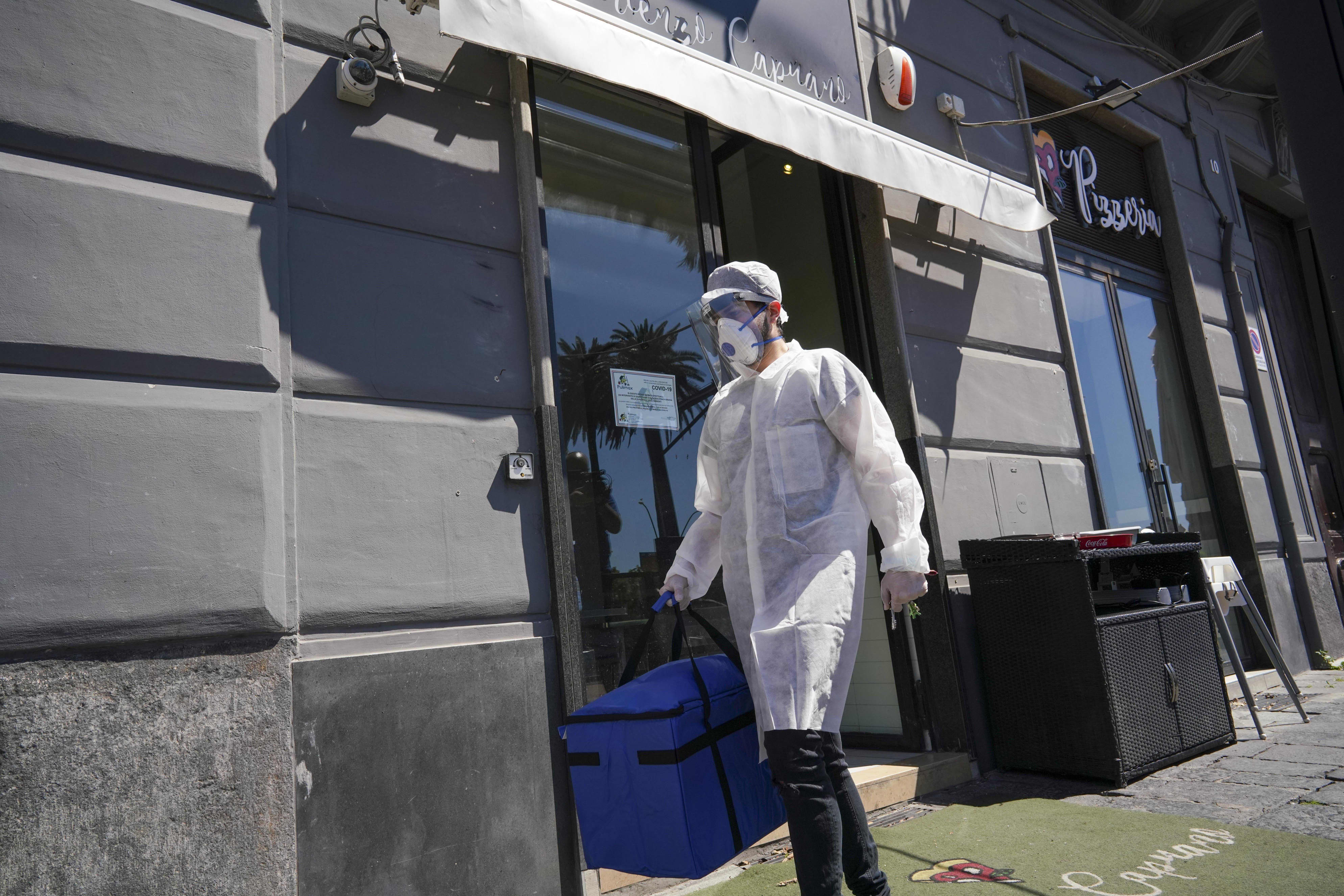 Image: A man carries pizza for home delivery at the Caputo pizzeria in Naples, Italy on Monday.