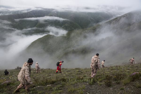 Rescue team members search an area near the crash site of a helicopter carrying Iranian President Ebrahim Raisi 