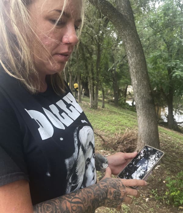 Amber Hensley searches through her phone for flash flood warnings that came July 4.