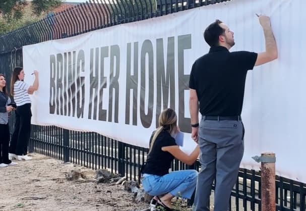 Well-wishers write messages of support for the family of Nancy Guthrie on a banner outside KVOA in Tucson.