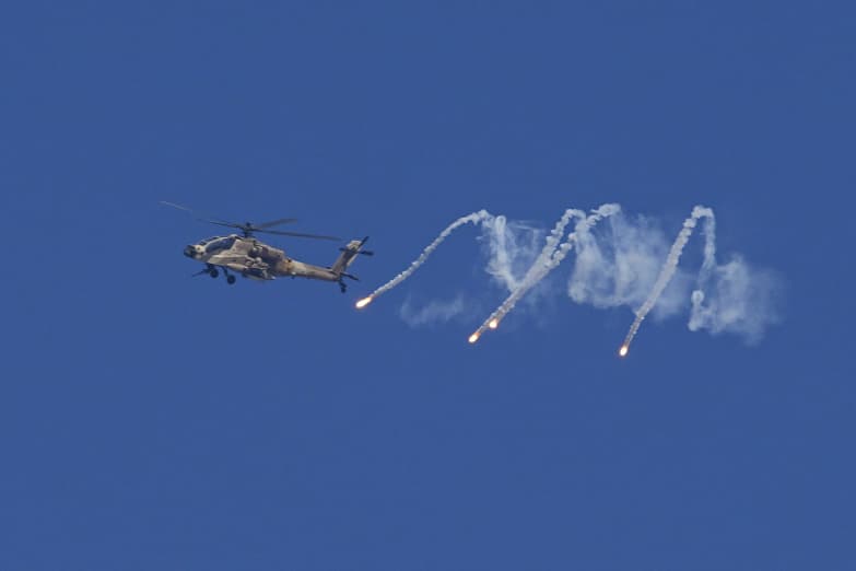 An Israeli military helicopter releases flares over the Israel-Gaza border as seen from southern Israel, Monday, Dec. 4, 2023.