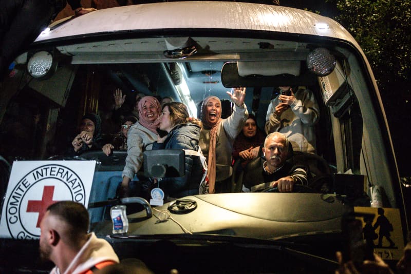 People wave from the inside of a bus