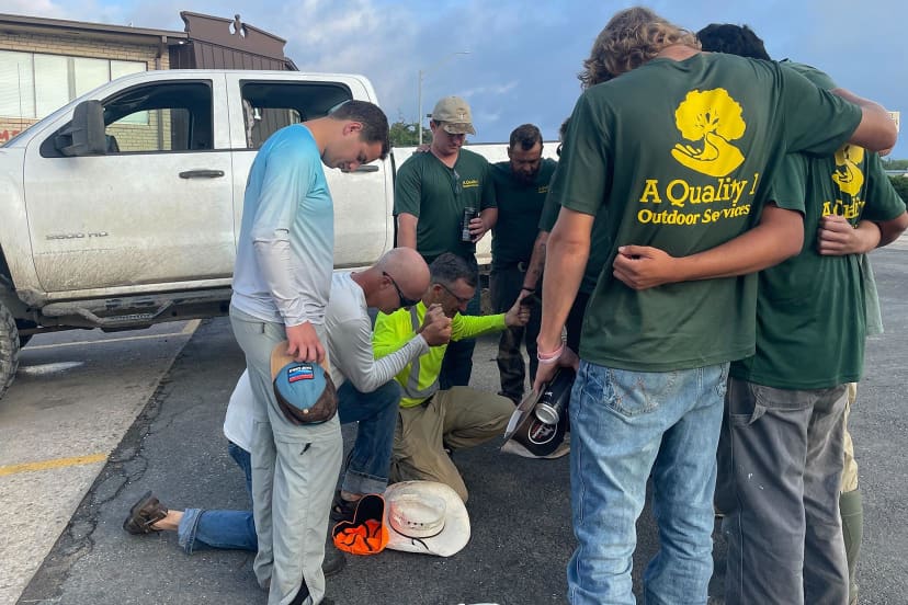 Sam Cummings and others pray before searching for victims at Heart O the Hills campground in Texas.