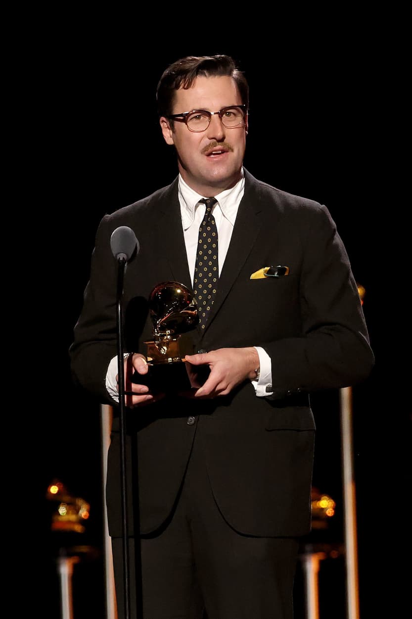 Nick Waterhouse hold a Grammy with both hands while speaking into a microphone.
