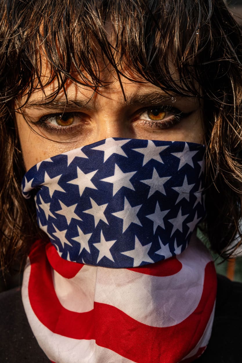 Image: A protester with an American flag bandana around their face.