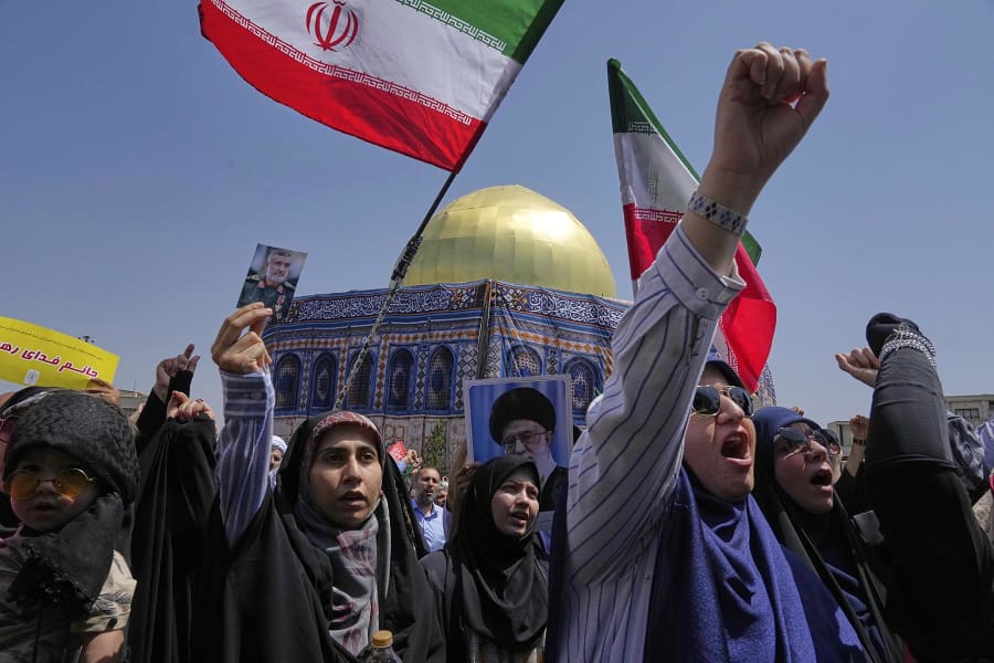 An Iranian protester holds a portrait of Iran's Revolutionary Guard aerospace division commander, Gen. Amir Ali Hajizadeh, who was killed in an Israeli strike on Iran, in front of a model of Jerusalem's Dome of the Rock mosque, during a protest after Friday prayers in Tehran on June 20, 2025.