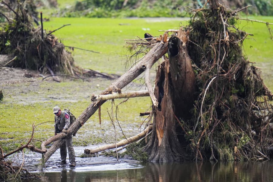 A Texas Department of Public Safety official inspects tree debris at Camp Mystic along the Guadalupe River after a flash flood swept through the area Sunday, July 6, 2025, in Hunt, Texas.