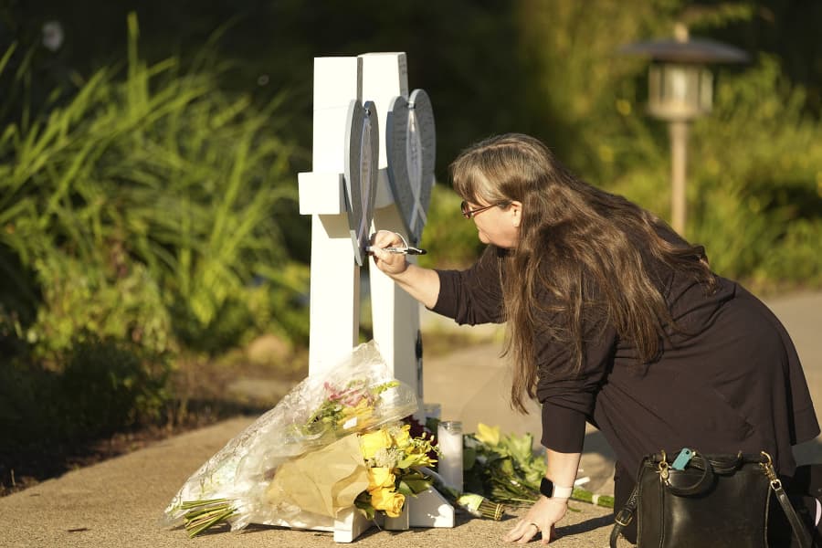 Katharine Barr writes on a memorial to victims at Annunciation Catholic Church, on Thursday, Aug. 28, 2025, the day after shootings at the school in Minneapolis.