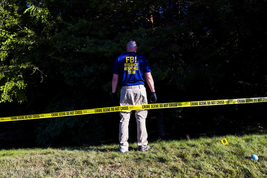An FBI agent stands in an area behind Utah Valley University where evidence was collected