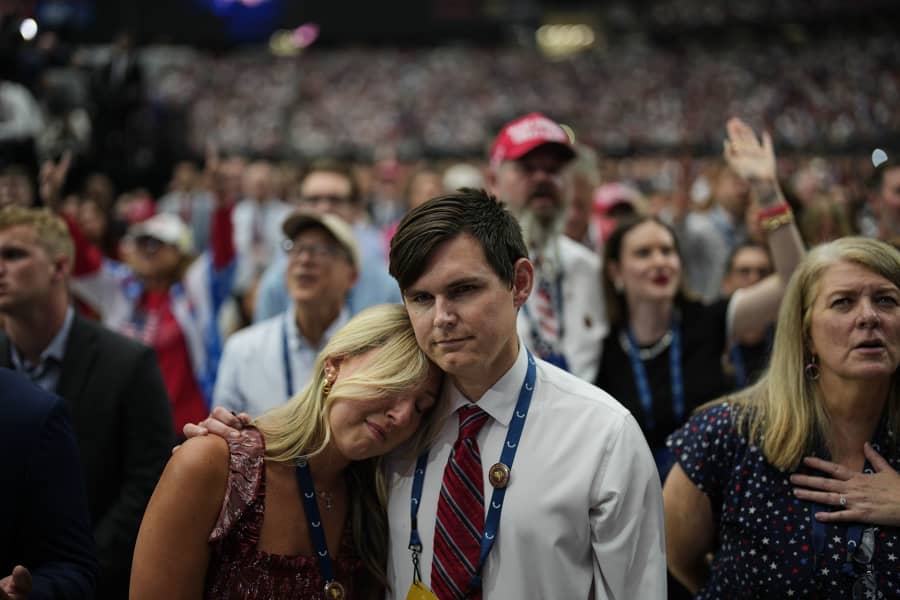 A woman is overcome with emotion while watching a Charlie Kirk tribute video during a memorial