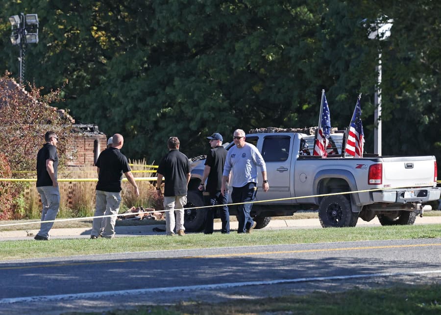 Law enforcement officials next to the vehicle used to ram the exterior of the Church of Jesus Christ of Latter-day Saints in Grand Blanc Township, Mich.
