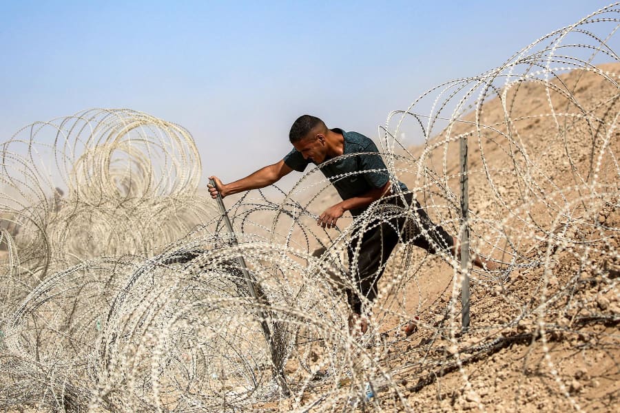 A man attempts to remove parts of the barbed-wire fence at the so-called "Netzarim corridor" near Nuseirat in the central Gaza Strip on Oct. 10, 2025, as people make their way back to Gaza City. 