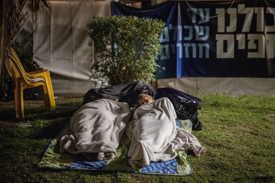 People sleep while waiting for the start of the hostage release live stream at Hostages Square in Tel Aviv