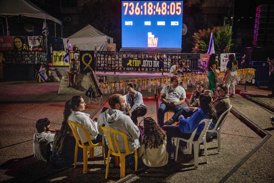 People sit in front of a clock counting the days the hostages have been in captivity at Hostages Square on Oct. 13, 2025 in Tel Aviv.