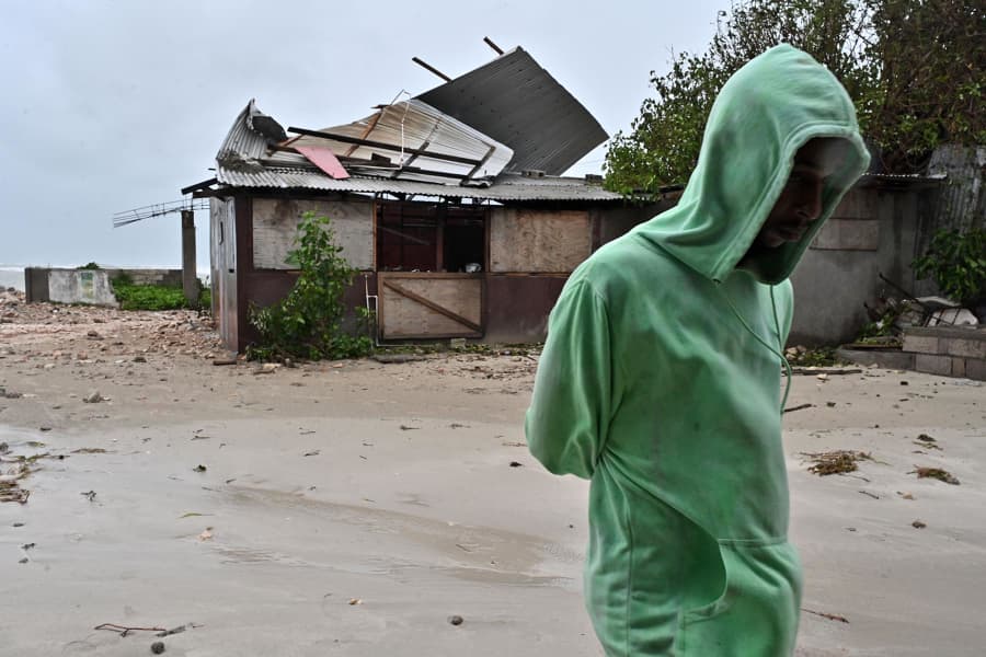 A man walks by a house damaged by the preliminary winds of Hurricane Melissa at Hellshire Fishing Beach in Portmore, Jamaica, on Oct. 27, 2025.
