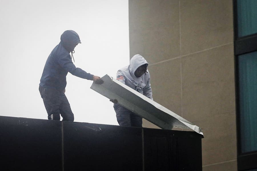Hotel staff removes a damaged gutter from the roof of AC Hotel Kingston in Kingston, Jamaica, on October 28, 2025. 