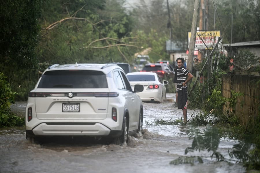 Vehicles maneuver on flooded road in St. Elizabeth, Jamaica on October 29, 2025.