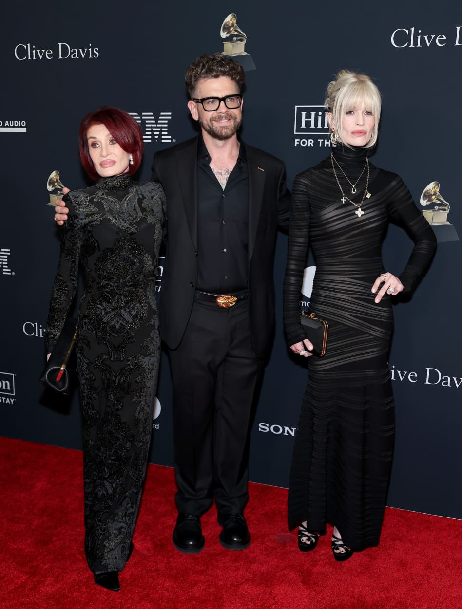 Sharon Osbourne, Jack Osbourne and Kelly Osbourne post for a photo in front of a step-and-repeat backdrop.