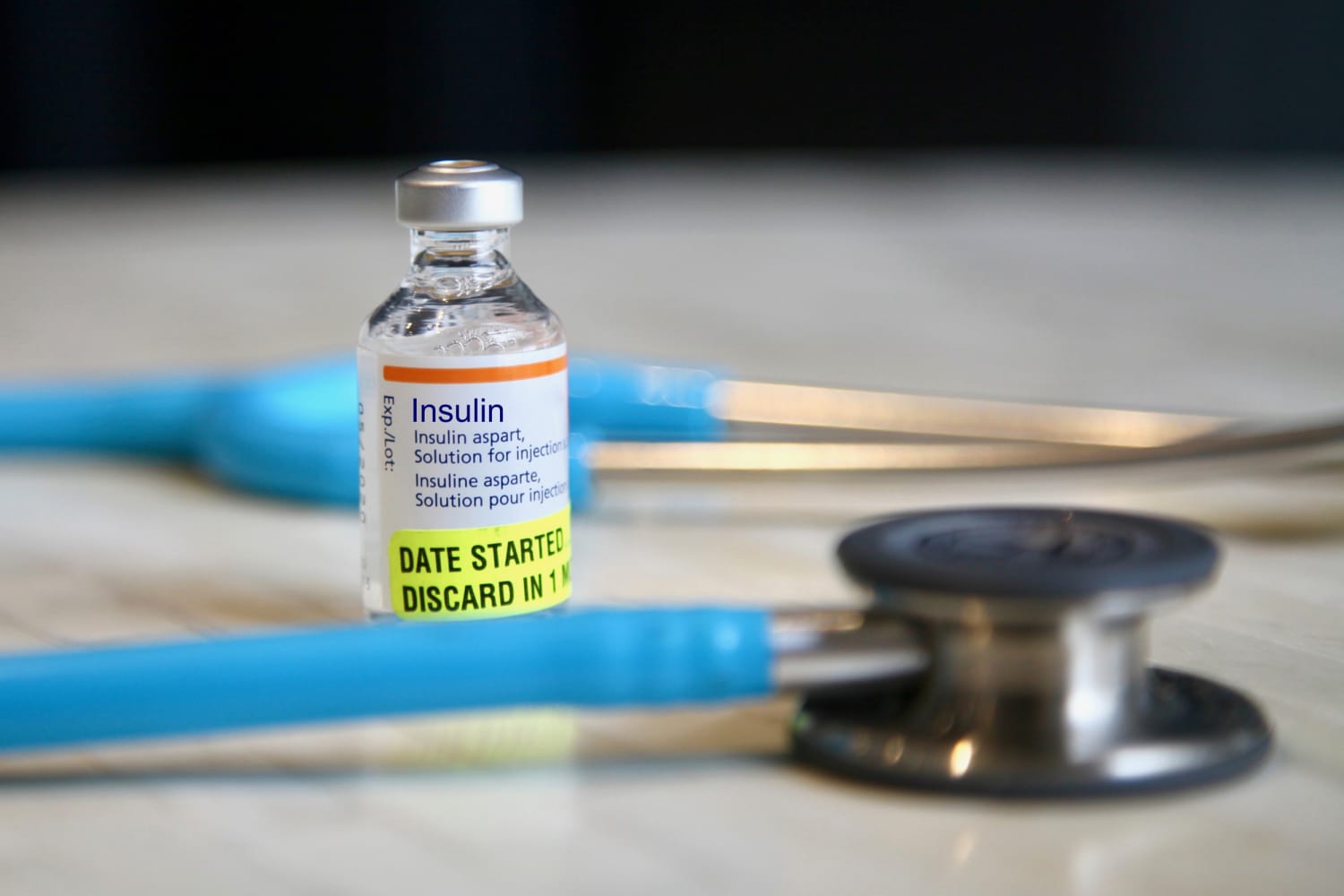 Top view of hands holding blue ribbon, symbol of World Diabetes Awareness  Day, on orange background of sugar with blood drop, caliper, measuring  tape, scattered pills, stethoscope and insulin syringes 27054888 Stock