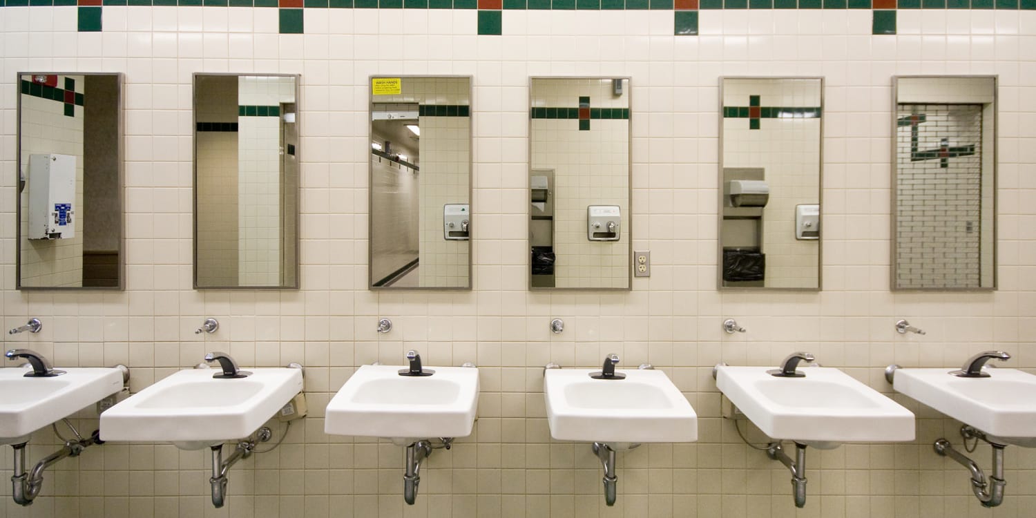 women standing at sink in public bathroom