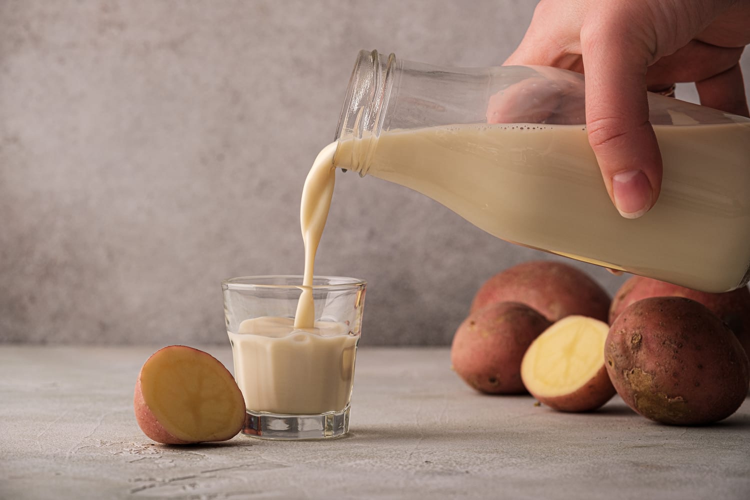 Head and shoulders of a baby girl eating a boiled potato - Stock