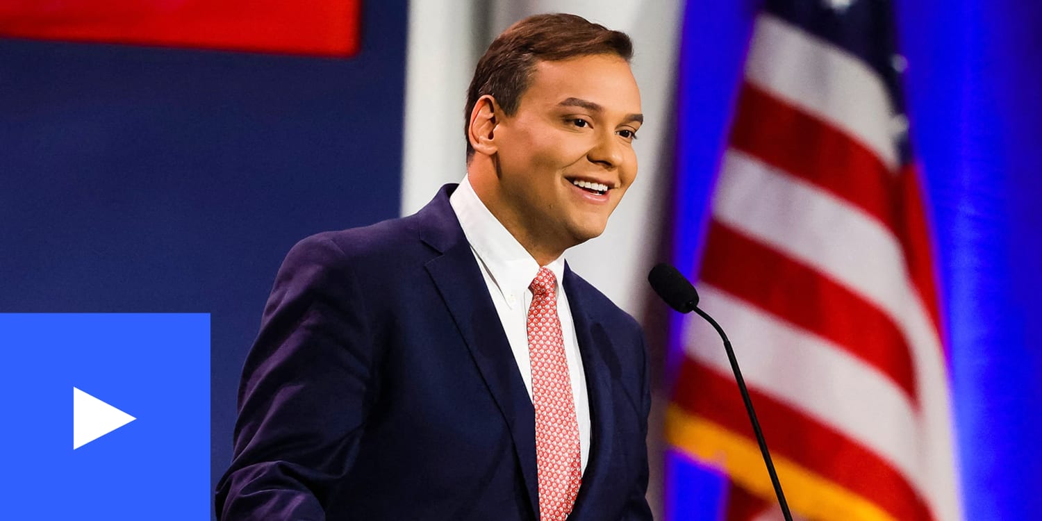 A photo of George Santos smiling at a podium