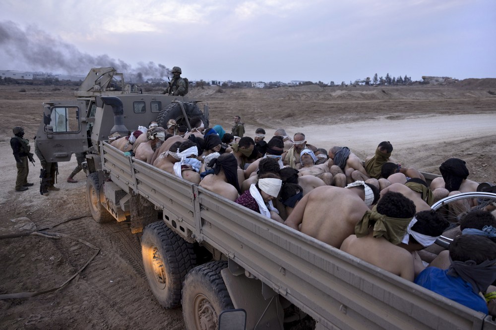 Israeli soldiers stand by a truck packed with bound and blindfolded Palestinian detainees in Gaza in 2023. Moti Milrod / AP file