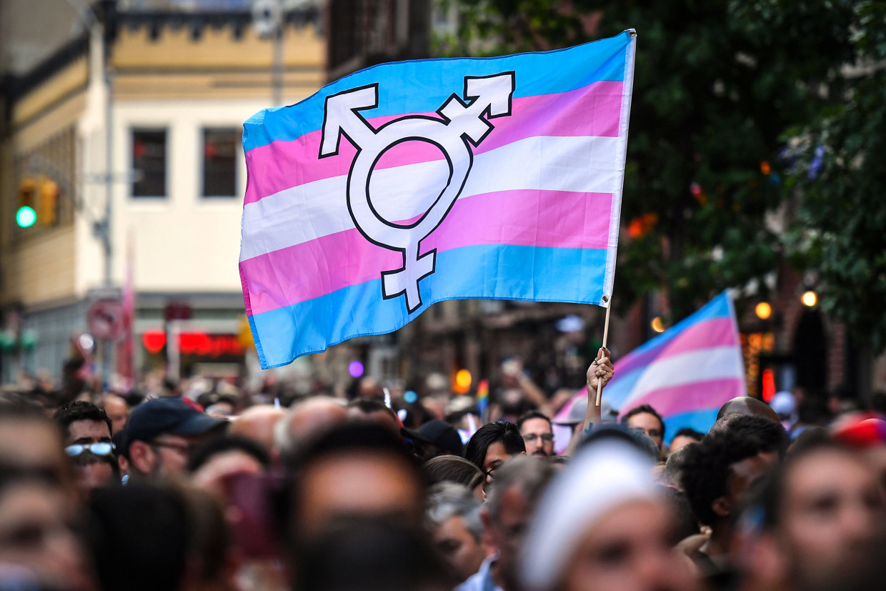 A person holds a transgender pride flag as people gather on Christopher Street outside the Stonewall Inn for a rally to mark the 50th anniversary of the Stonewall Riots in New York on June 28, 2019.