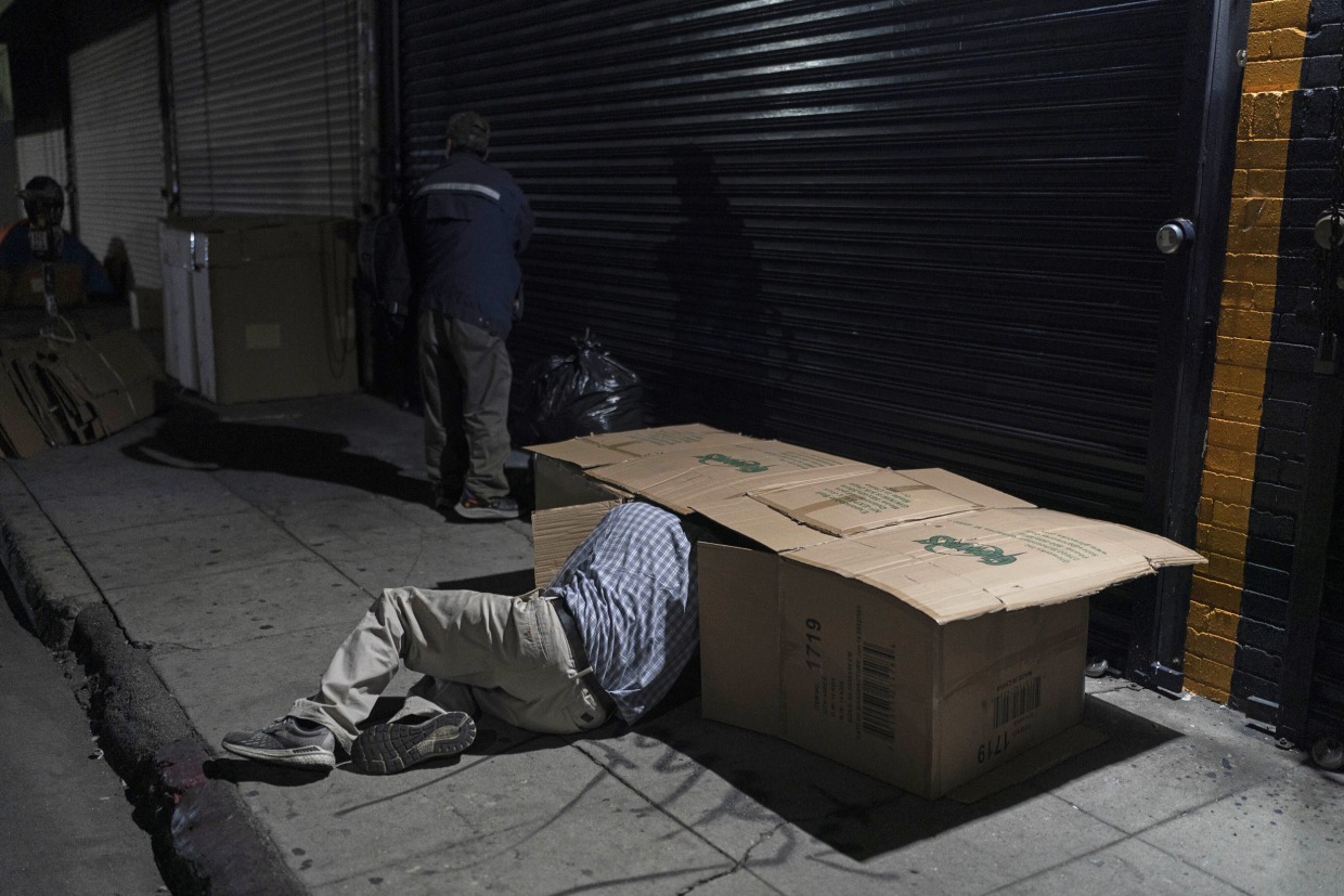 David Hernandez, a 62-year-old homeless man, crawls into his bed made with cardboard boxes in Los Angeles on Dec. 14, 2022. 