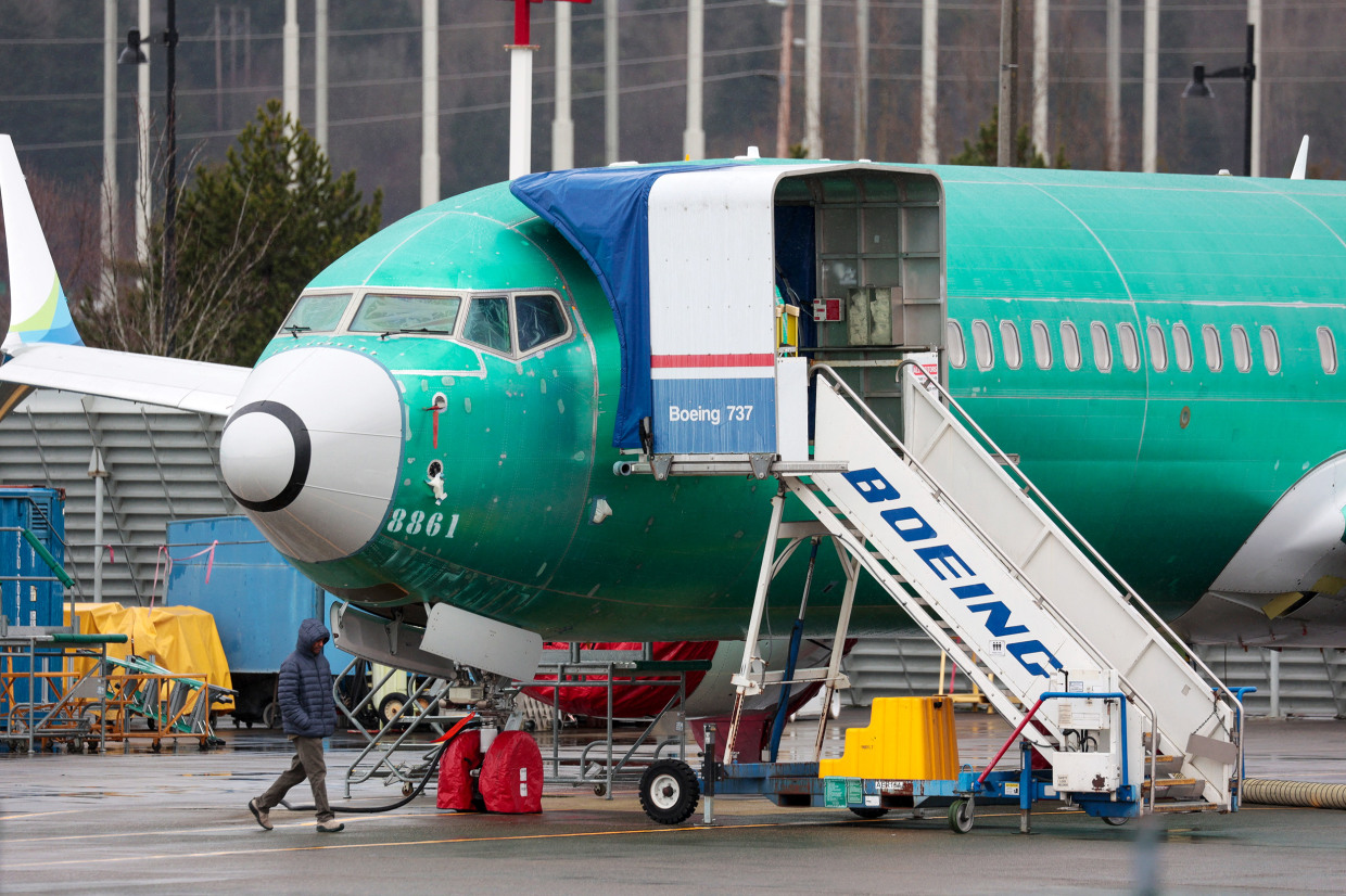 A person walks past an unpainted Boeing 737-8 MAX